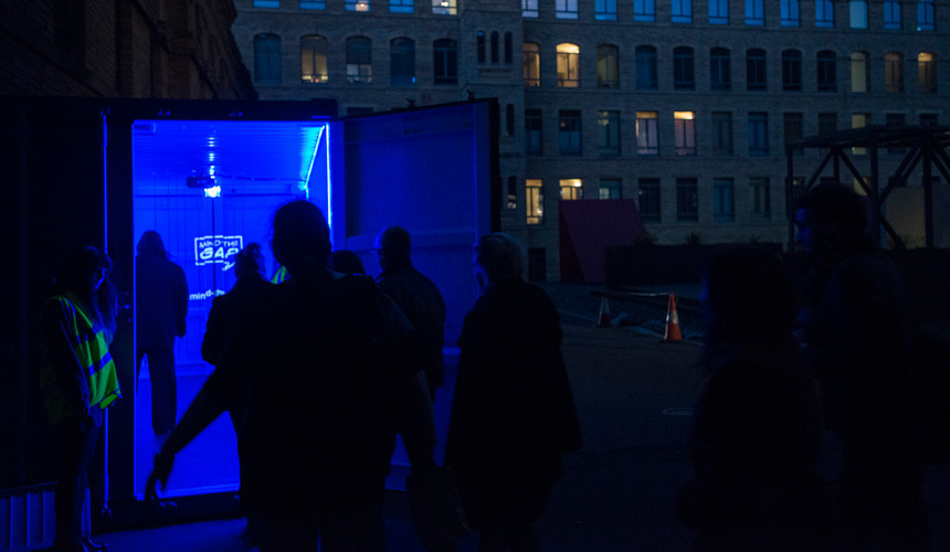 A group of people entering a bright blue shipping container.